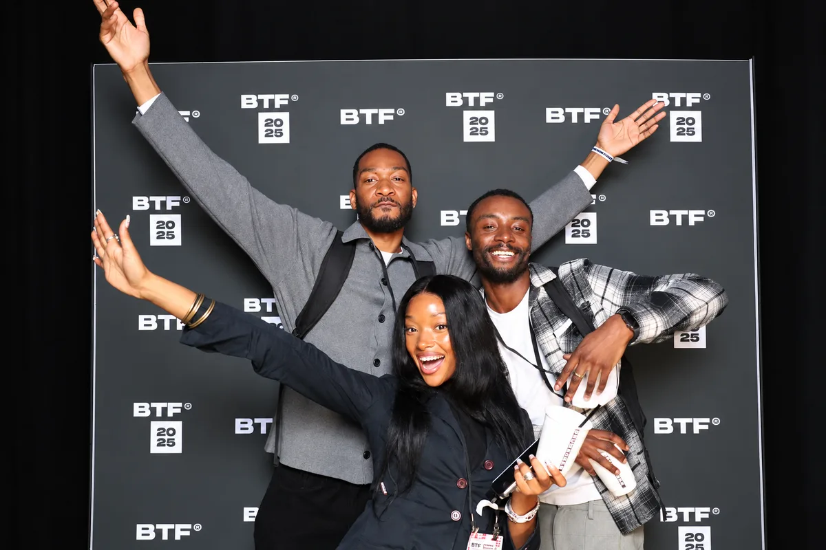 Three guests celebrating in front of a BTF branded photo booth backdrop
