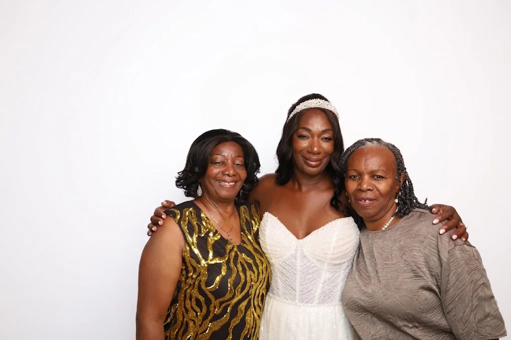 A bride posing with two guests at a wedding photo booth experience